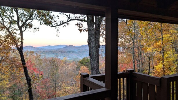 Une terrasse en bois offrant une vue sur une chaîne de montagnes boisées.