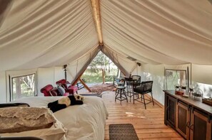 Un hébergement sous tente comprenant un lit, un coin salon et une vue sur l’extérieur.