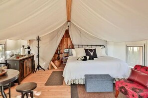 Relax in a cozy tent-style accommodation with a comfortable bed, sofa, and seating area.