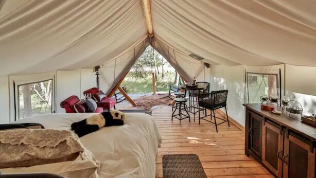 Un hébergement sous tente comprenant un lit, un coin salon et une vue sur l’extérieur.