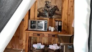Un chalet confortable avec un intérieur en bois, un tableau représentant un cavalier, un four à micro-ondes et deux paniers posés sur le sol.