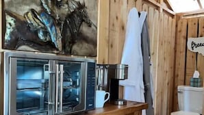 L’intérieur d’un chalet en bois comprend un coin cuisine, un tableau représentant un cheval et des toilettes rustiques.