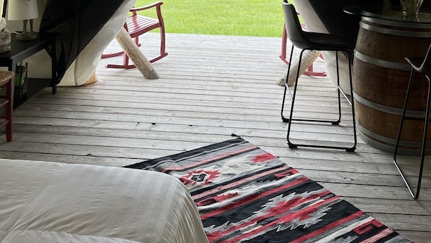 Een tent met een bed, een stoel, een tafel en een vloerkleed.