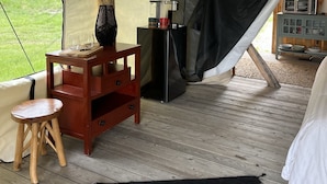 Een tent met een houten tafel, een zwarte kast en een tapijt met dessin.
