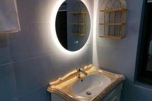 A bathroom with a round mirror, a sink, and two wall-mounted light fixtures. - Ruisiyuan Inn (Huzhou)