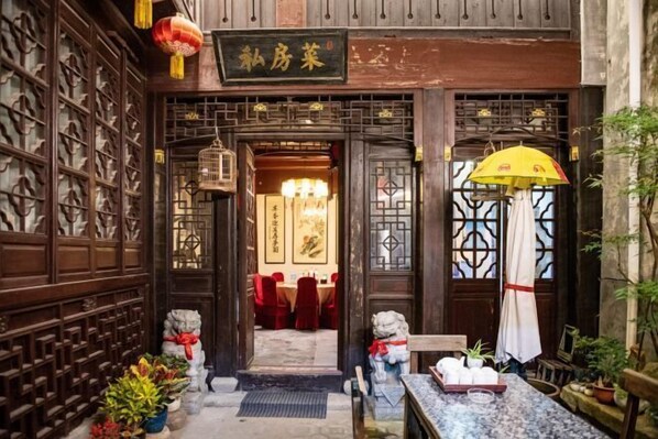 A traditional Chinese restaurant entrance with wooden lattice doors, a signboard, and a table set with dishes outside. - Ruisiyuan Inn (Huzhou)