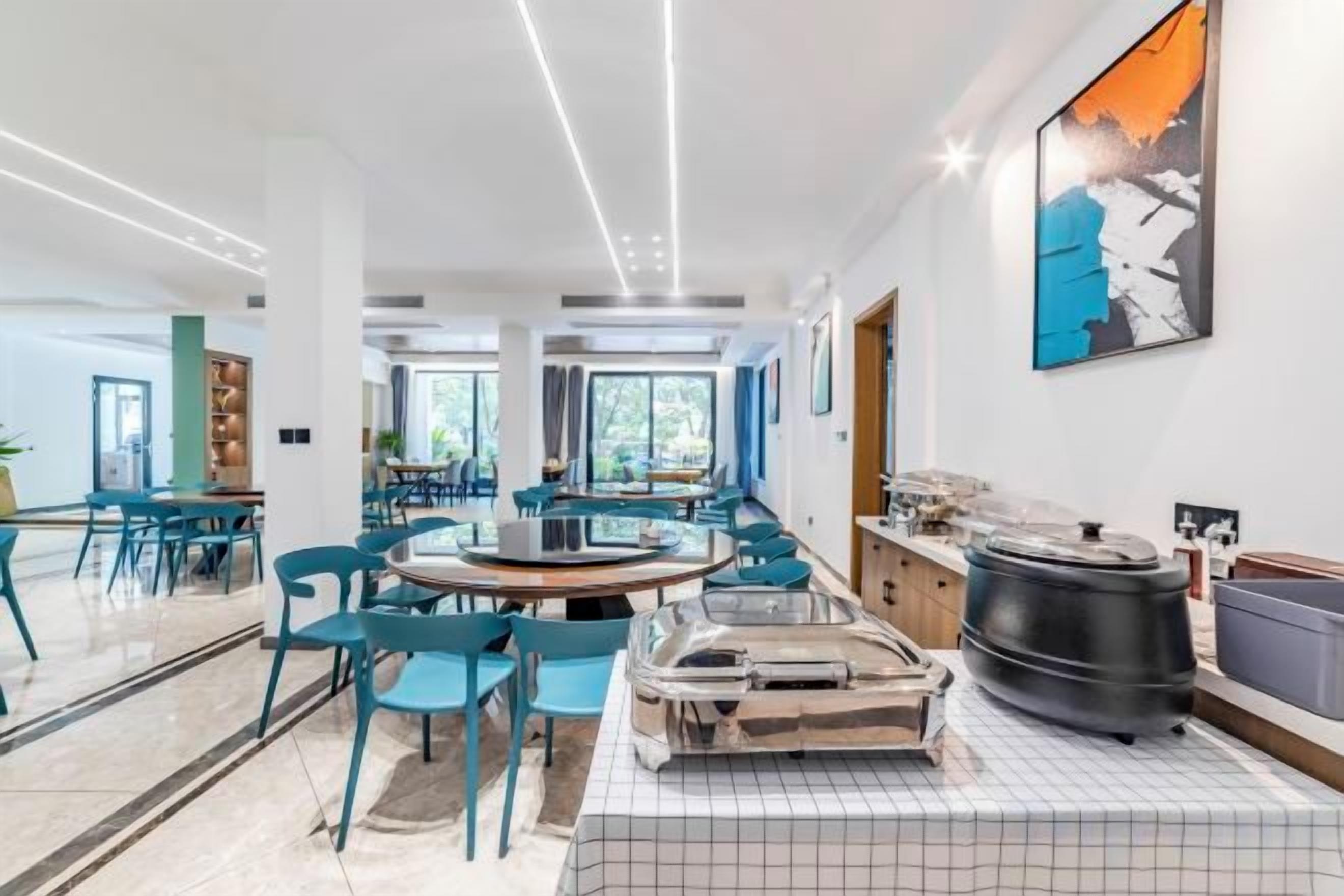 Una zona de dinar moderna amb taules rodones, cadirees i un quadre gran a la paret.
