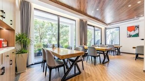 A modern conference room with wooden tables and chairs, large windows with curtains, and a ceiling with recessed lighting. - Anji Shanya Minsu Guesthouse (Anji)