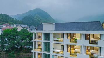 A multi-story hotel with balconies, each with a bed and a view of the surrounding landscape.