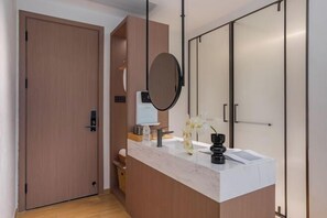A modern bathroom with a wooden door, a marble countertop, a round mirror, and a small sink. - Anji Shanya Minsu Guesthouse (Anji)
