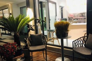 Un interior moderno con piso de madera, dos sillas, una mesita y plantas en macetas.