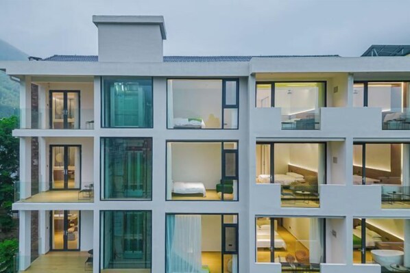 Un hotel modern d'alguns pisos amb grans finestres, balcons i una escala central.