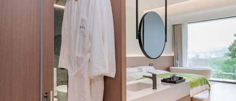 A modern bathroom with a wooden vanity, a large mirror, and a view of the city.