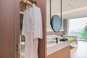 Un baño moderno con tocador de madera, un espejo grande y vistas a la ciudad.