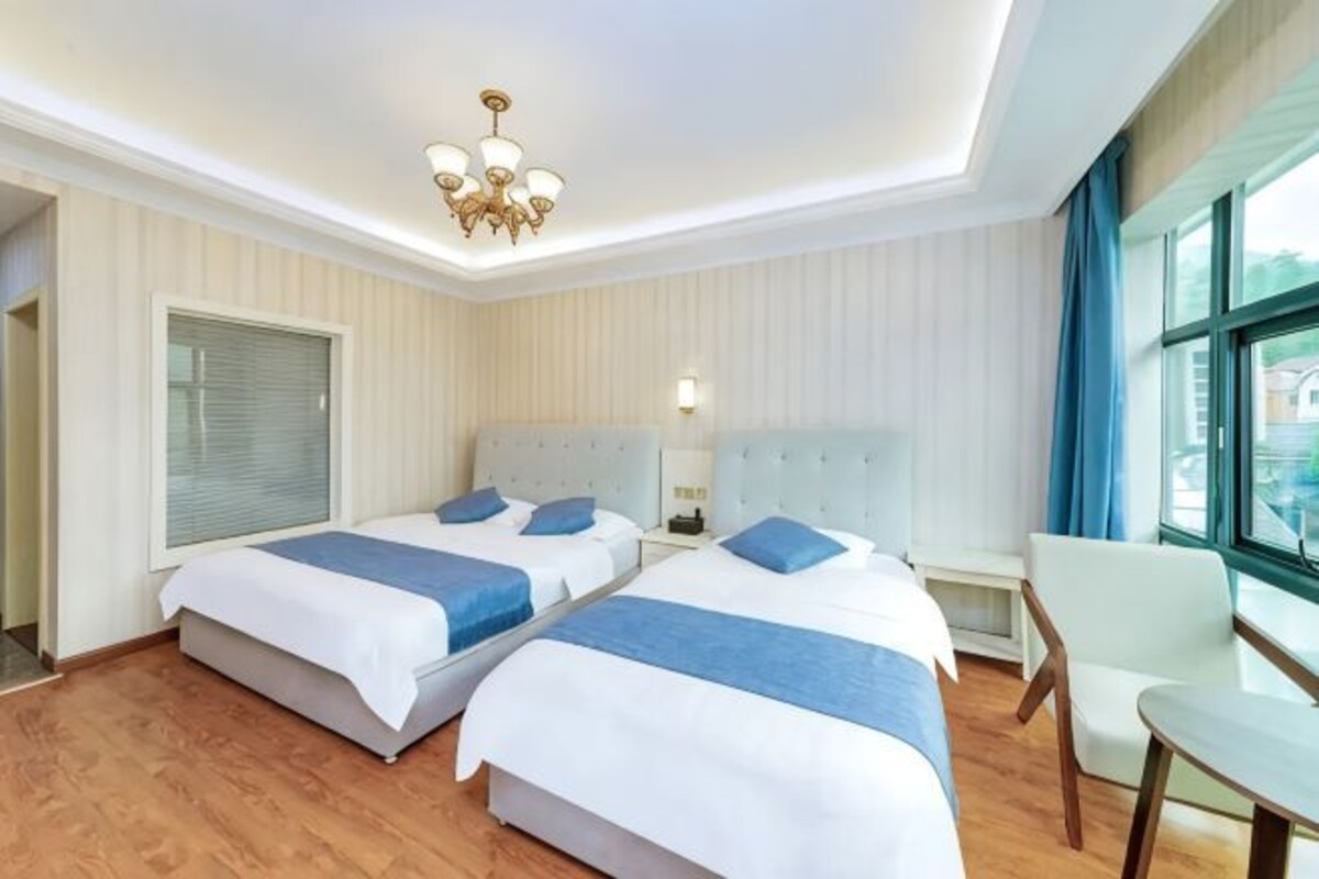 A hotel room with two beds, a dining table, and a view of the city.