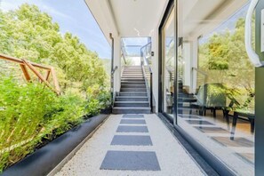 A modern staircase leading to a glass door entrance, surrounded by greenery and a clear sky. - Anji Shanya Minsu Guesthouse (Anji)