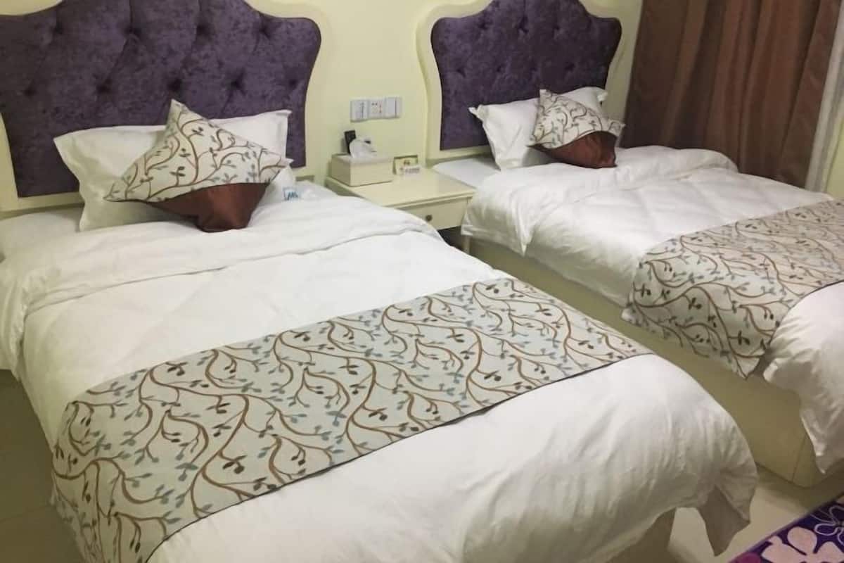 Two twin beds with headboards, white bedding, and patterned throw pillows.