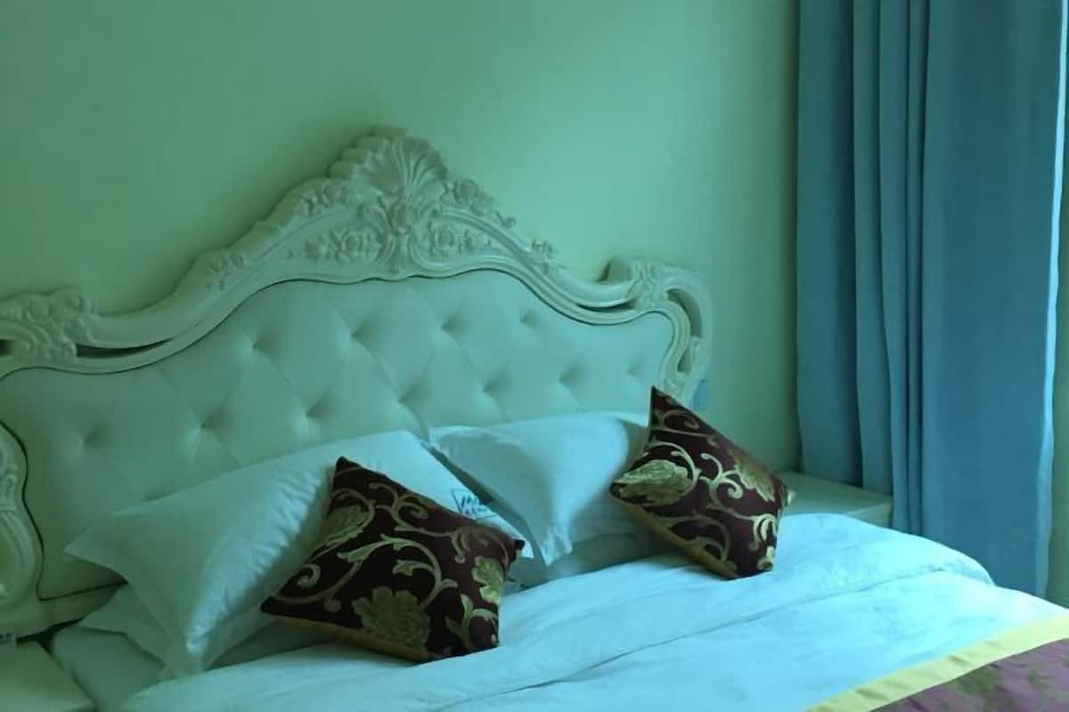 A bed with a tufted headboard, white bedding, and patterned pillows.