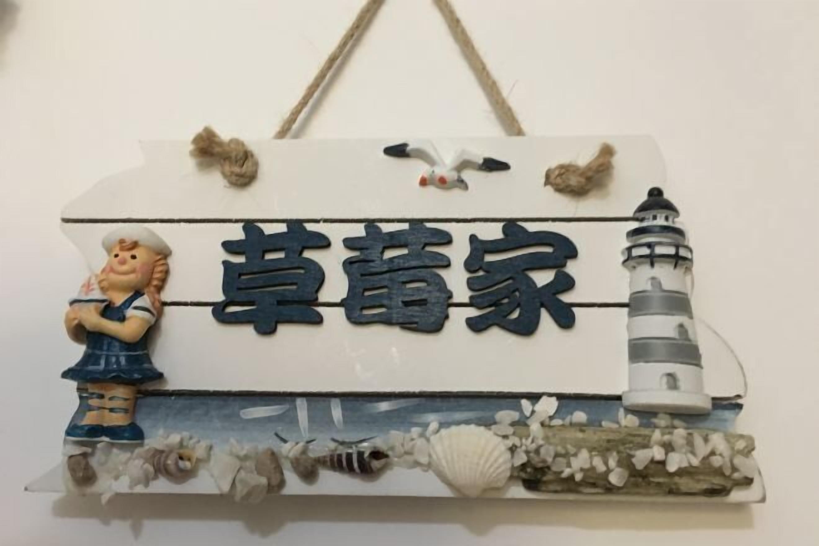 A decorative sign with a lighthouse and a figure, possibly a chef, with the text "草蕾家".