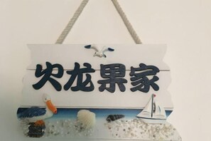 Segno con caratteri cinesi ed elementi decorativi tra cui un cigno, una nave e conchiglie.
