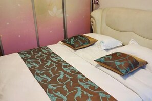 A bed with a patterned bedspread, two pillows with a leaf design, and a headboard. - Aimo Inn (Deqing)
