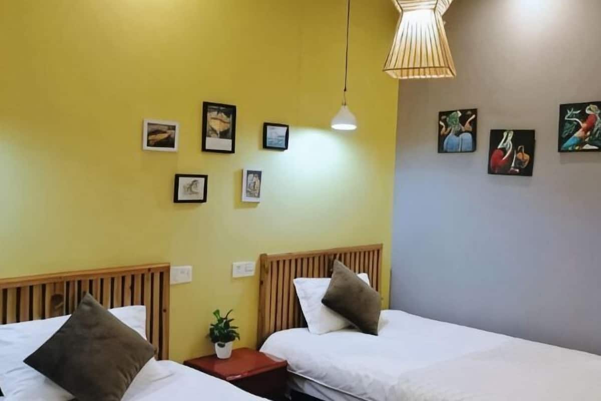 Una habitación con dos camas, un cabecero de madera, una mesita con una planta y decoración en la pared.