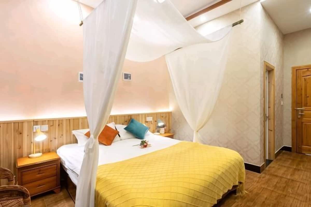 Un dormitorio con una cama, mesitas de noche, una silla y una puerta de madera.