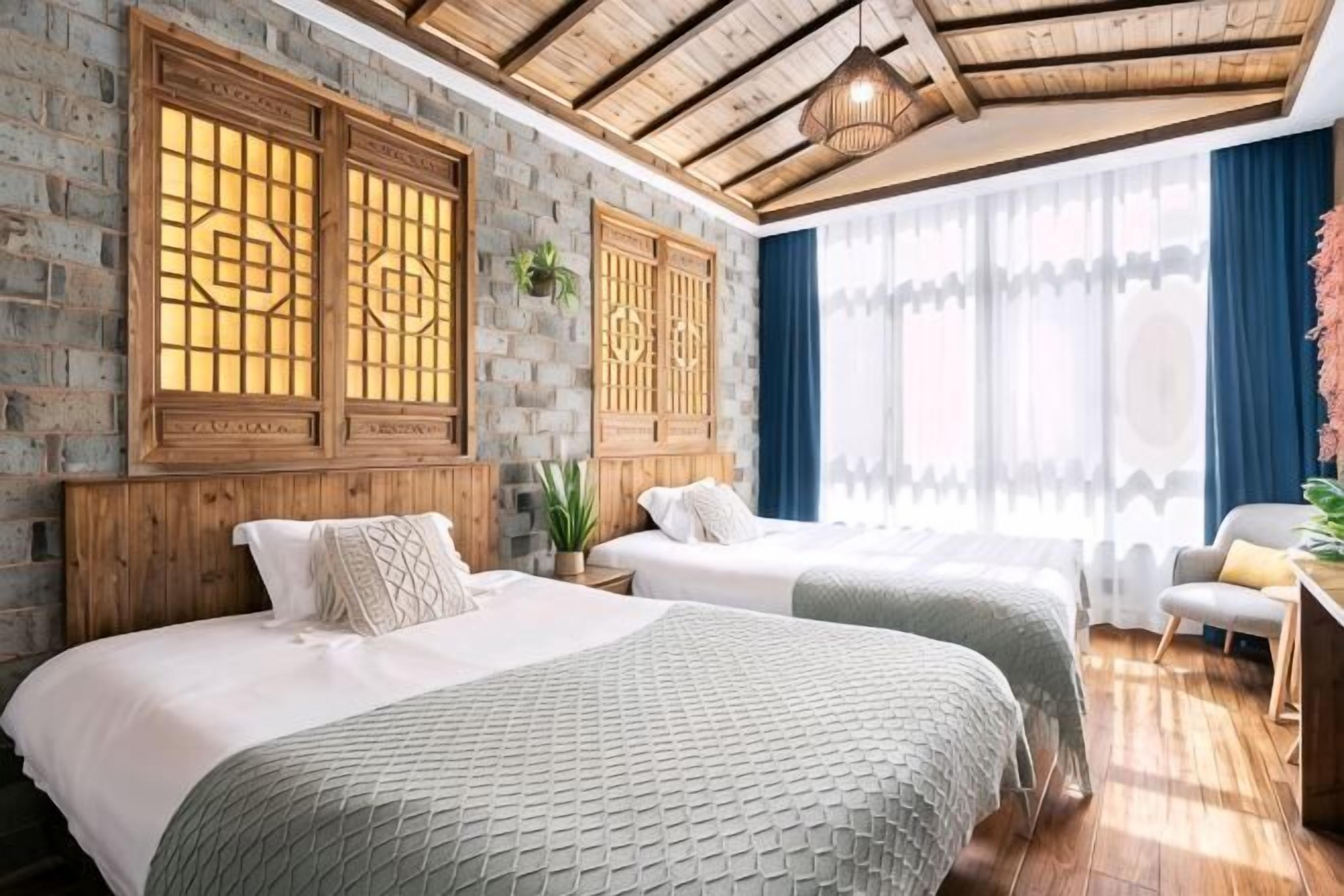A room with two beds, a desk, and a window with curtains.. Wenjunge Jingju