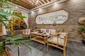 A traditional-style room with a wooden sofa set, a dining table, and a large painting on the wall.