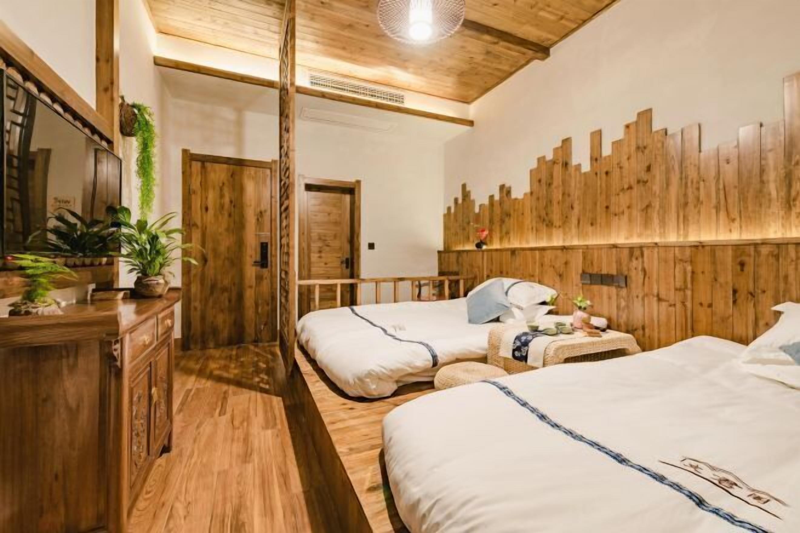 Una habitación con dos camas, paredes y techo de madera, y un espejo.