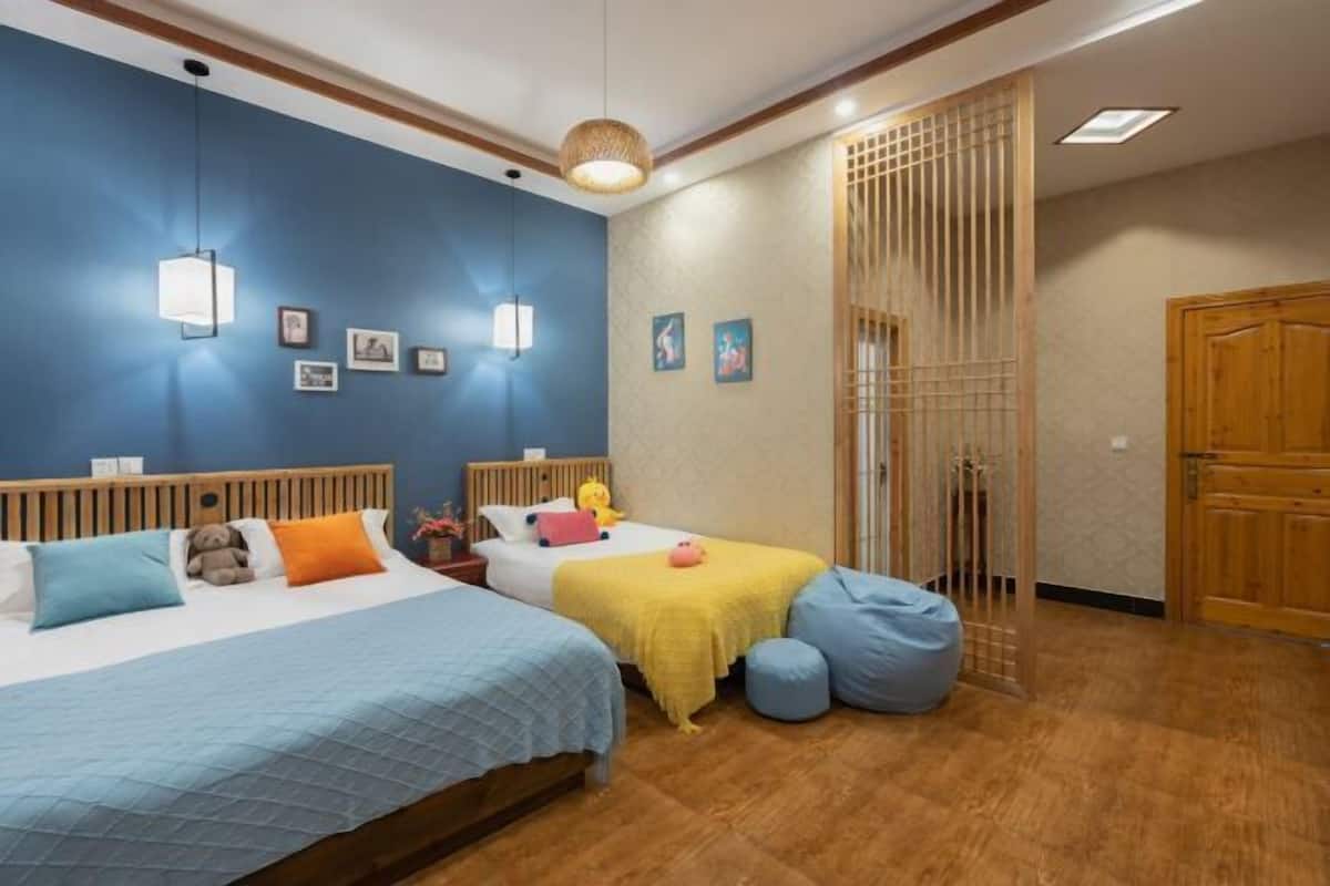Un dormitorio con dos camas, un cabecero de madera, una pared azul y suelo de madera.