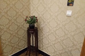 A corner with a patterned wallpaper, a wooden stool with a potted plant, and a Wi-Fi sign on the wall. - Wenjunge Jingju (Wuyuan)