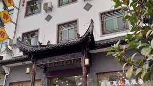 Un edificio tradicional con techo de tejas y varias ventanas, algunas con rejas decorativas.