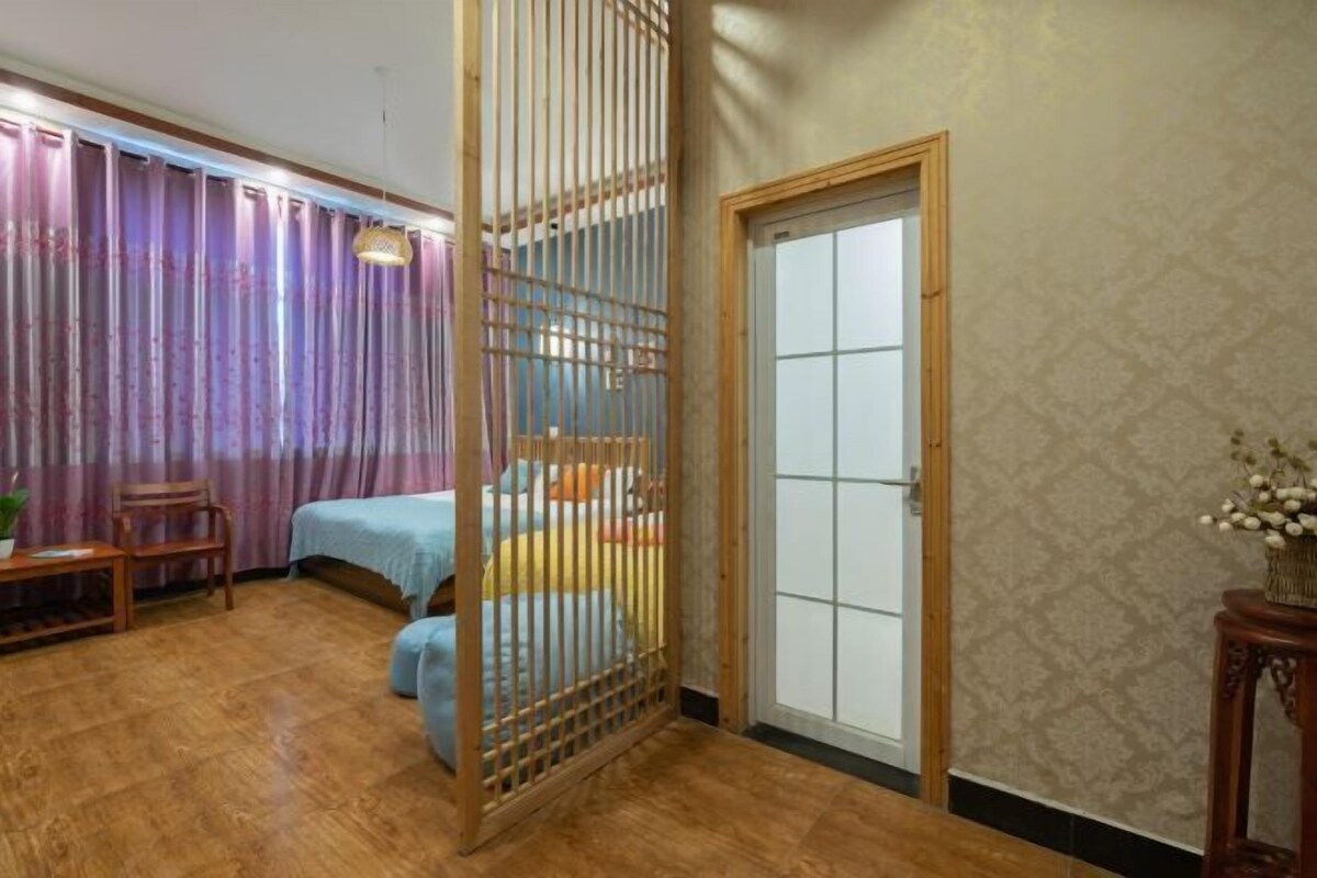 A room with a bed, a wooden partition, a chair, and a small table.