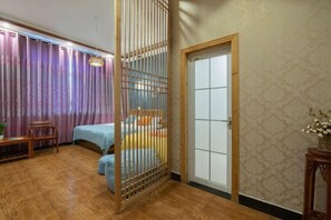 A room with a bed, a wooden partition, a chair, and a small table. - Wenjunge Jingju (Wuyuan)