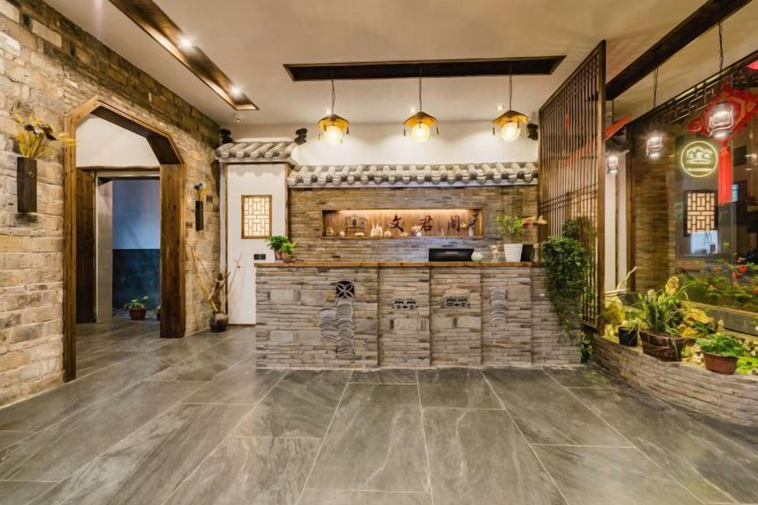 A reception area with a stone counter, hanging lights, and a brick wall.