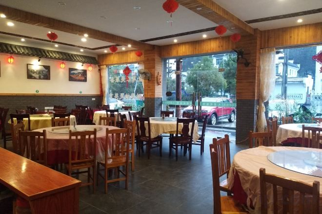 A restaurant with multiple tables and chairs, large windows, and a view of the outside.