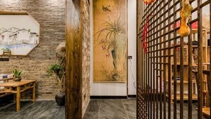 Un interior tradicional con una puerta de madera, un cuadro enmarco y un banco de madera.