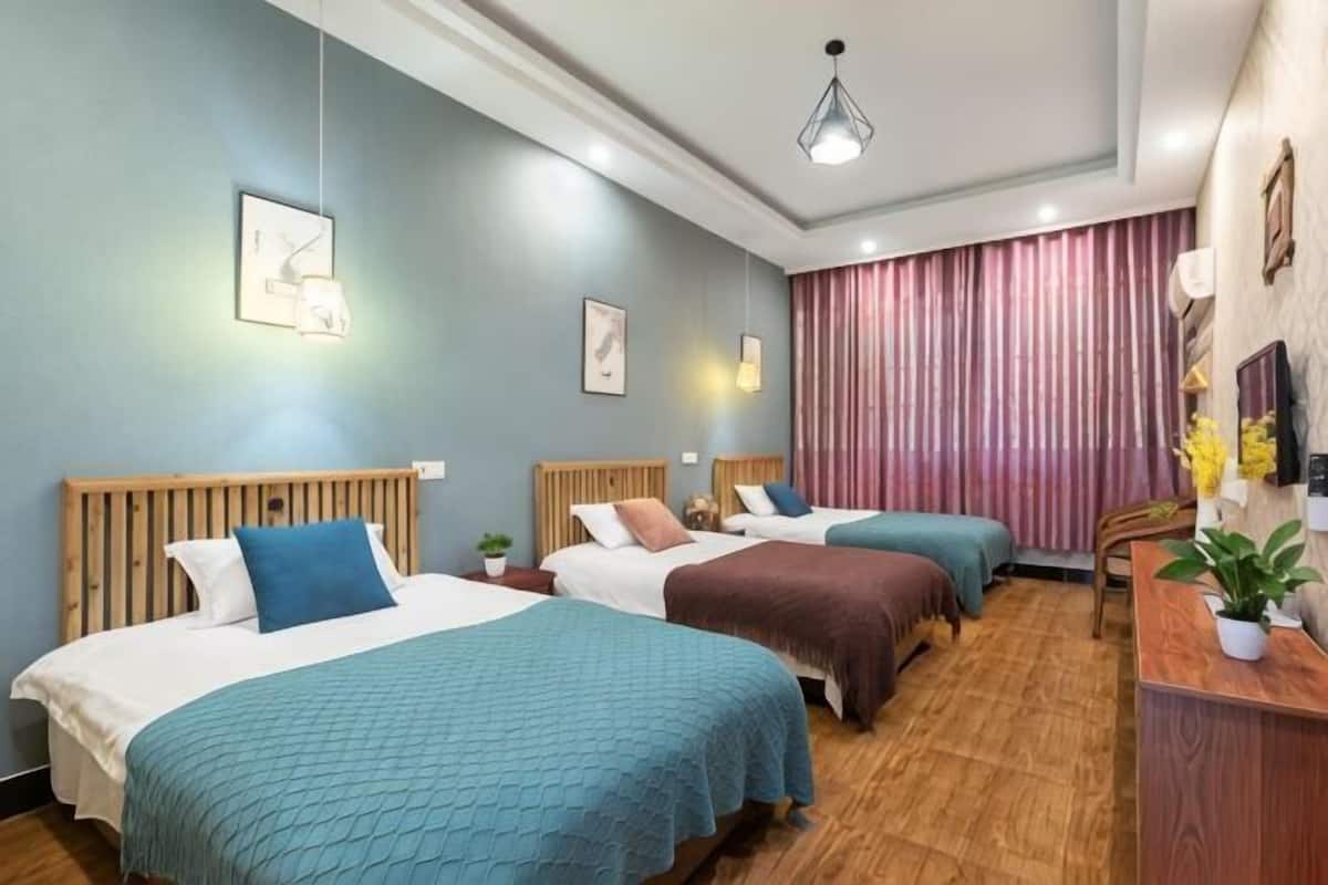 Habitación de hotel con dos camas, un escritorio y una ventana con cortinas.