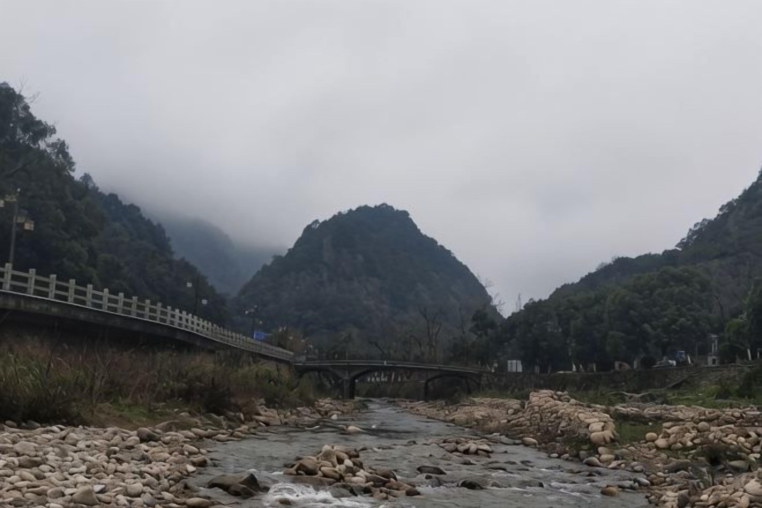 Un río con un puente, rodeado de montañas y vegetación.