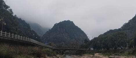 Un río con un puente, rodeado de montañas y vegetación.
