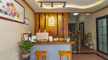 A reception area with a wooden reception desk, two bar stools, a computer, and framed pictures on the wall.
