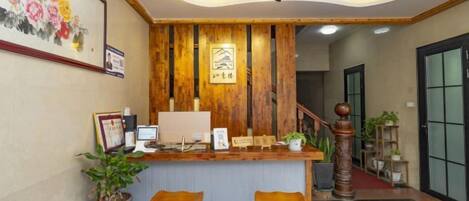 A reception area with a wooden reception desk, two bar stools, a computer, and framed pictures on the wall.