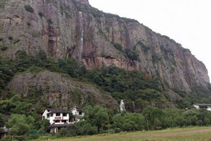 Un paysage montagneux avec une maison et une statue.