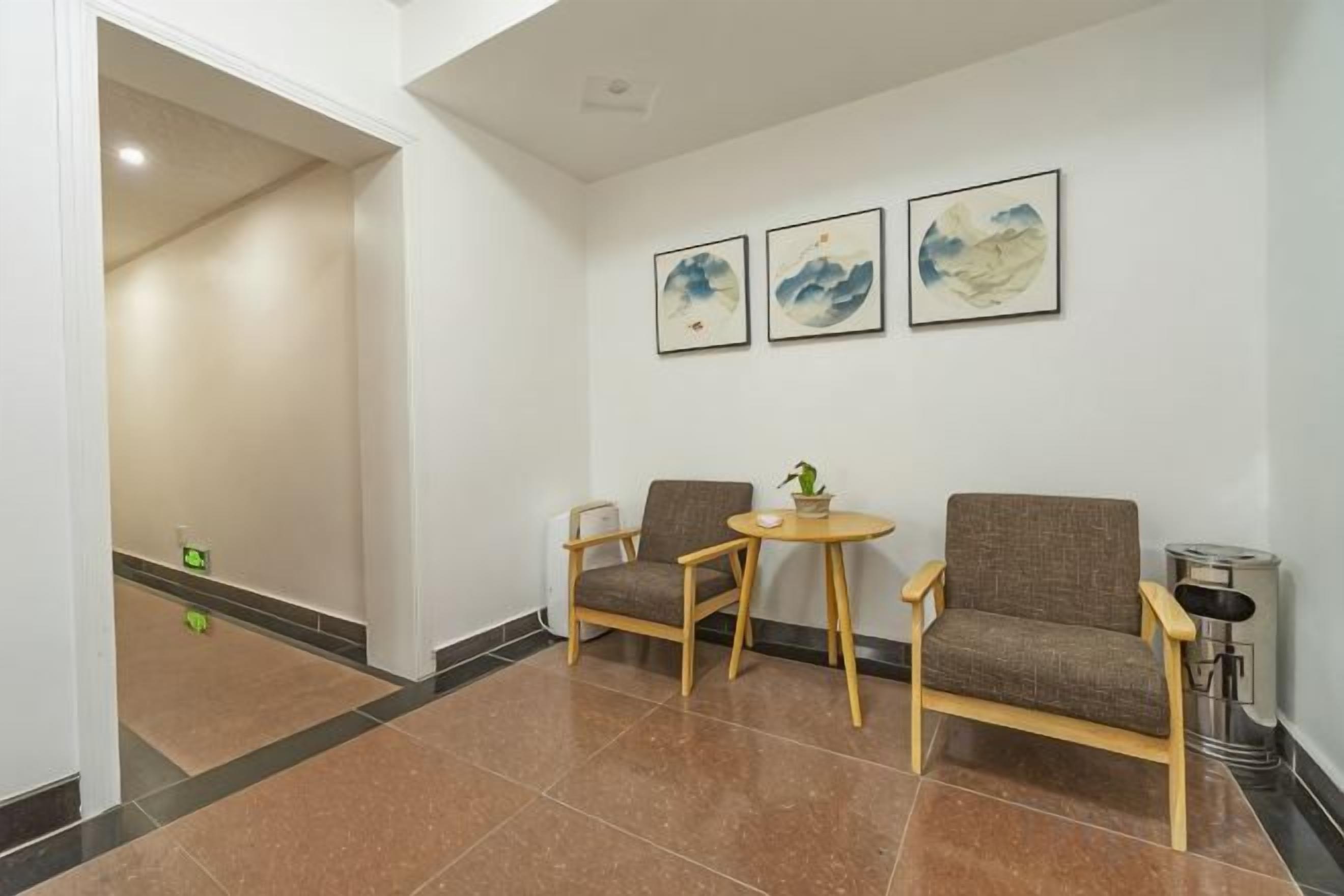 A hotel lobby with a reception desk, two sofas, a small table, and artwork on the wall.