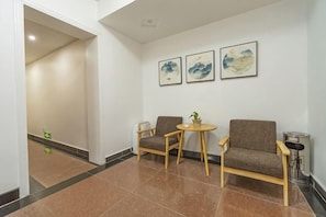 A hotel lobby with a reception desk, two sofas, a small table, and artwork on the wall. - Ruyilou Hostel (Yueqing)