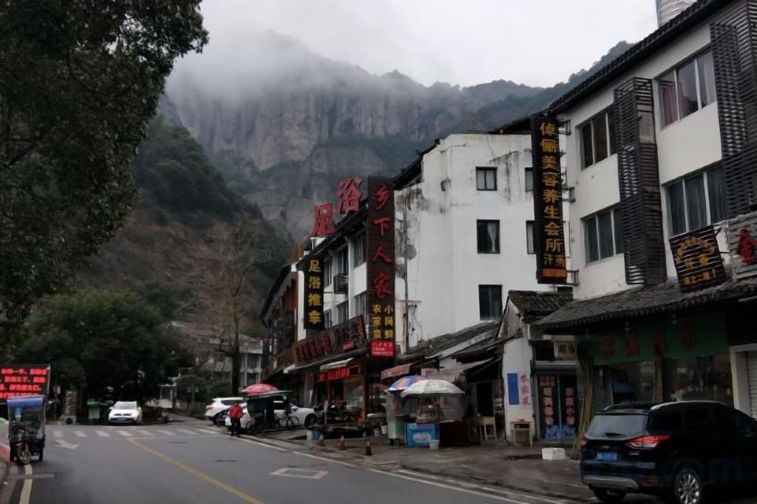 A street with buildings, a mountain in the background, and vehicles.
