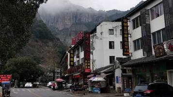 A street with buildings, a mountain in the background, and vehicles.