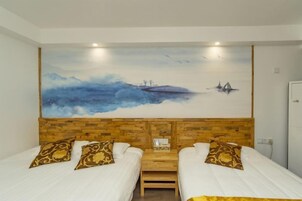 Habitación con dos camas, cabecero de madera, ropa de cama blanca y un cuadro grande de un paisaje en la pared.