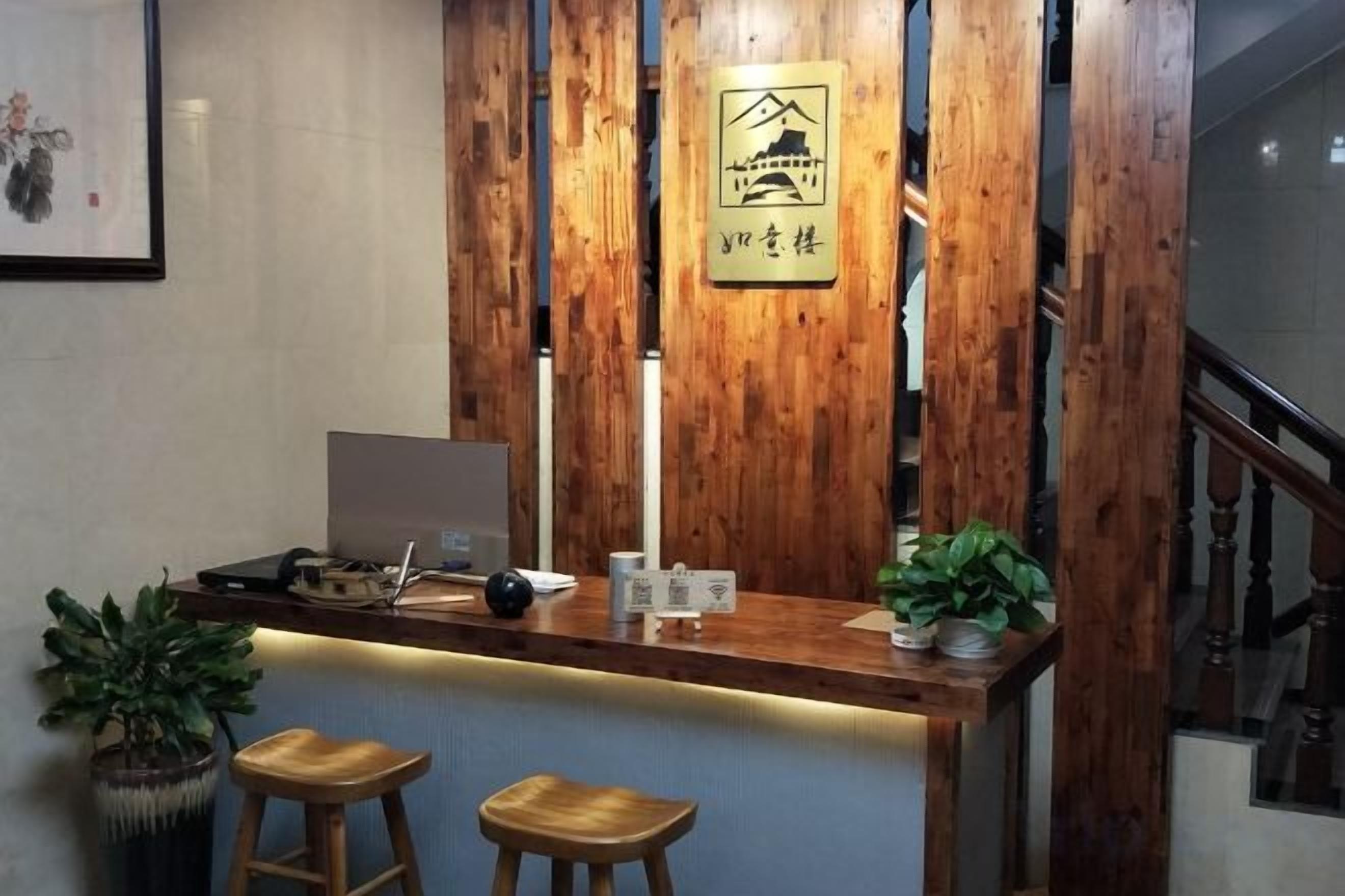 Un mostrador de recepción con una computadora portátil, una planta en maceta y un cartel que indica un restaurante.